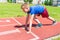 Caucasian boy,kid prepare to start running on a red track.young boy in starting position ready for running.Summer day