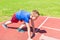 Caucasian boy,kid prepare to start running on a red track.young boy in starting position ready for running.Summer day