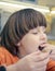 Caucasian boy with long light hair is eating chocolate sitting at the table in casual clothes. Portrait.