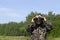 Caucasian boy in masking camouflage uniform with binoculars. Plays military or hunter