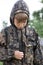 Caucasian boy in masking camouflage uniform saddened outdoor