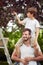 Caucasian boy sitting on father`s shoulders picking cherries