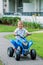 Caucasian boy toddler driving blue electric car on the road