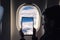 Caucasian boy using tablet pc taking picture through airplane window clouds with sky