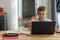 Caucasian boy waving hand while attending online class over laptop at home, copy space