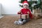 Caucasian boy wearing a red santa claus hat. sitting near a Christmas tree unties a bow on a large box with a gift.