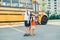 Caucasian boys students holding waving Canadian flag. Students kids near yellow school bus. Education and back to school in