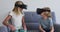 Caucasian brother and sister gesturing while using vr headset sitting on the couch at home