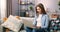 Caucasian brown haired woman using her laptop computer, while sitting on sofa at home. Motivated millennial female