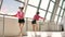 Caucasian brunette in pink sportswear drinking water from bottle in white room