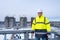 Caucasian builder in white working helmet and a yellow jacket looking at the camera