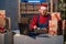 Caucasian business owner working with product packaging and laptop wearing a Sanat Claus hat and red sweater. Glue