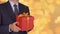 Caucasian businessman hold and give red gift box. From unfocus to focus motion. Adult man in classic business suit hold