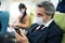 Caucasian businessman wearing face mask using mobile phone on airplane during covid pandemic to prevent coronavirus infection. The