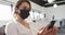 Caucasian businesswoman wearing face mask and using smartphone in office