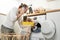Caucasian busy father doing housework with baby boy toddler in kitchen. Attractive man use phone call for work and put clothes to