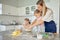 Caucasian caring mother and little daughters baking together in a kitchen at home. Mom teaching girls how to make dough