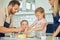 Caucasian caring parents and their little daughters baking together in a kitchen at home. Mother and father teaching