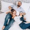 Caucasian cheerful family lies on a white bed. View from above.