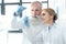 Caucasian chemists in white coats looking at tube in chemical laboratory