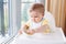 Caucasian child boy with dirty messy face sitting in high chair eating apple puree