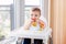 Caucasian child boy with dirty messy face sitting in high chair eating apple puree with spoon