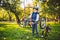 Caucasian child boy in a helmet learns to repair his bike. Child cyclist checks the mechanism of a bicycle in a clearing of green