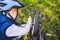 Caucasian child boy in a helmet learns to repair his bike. Child cyclist checks the mechanism of a bicycle in a clearing of green