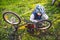 Caucasian child boy in a helmet learns to repair his bike. Child cyclist checks the mechanism of a bicycle in a clearing of green