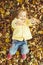 Caucasian child girl dressed in a jacket lies on the ground in autumn leaves