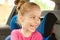 Caucasian child girl laughing while traveling in a car seat