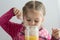 Caucasian child of three years old taking honey using spoon from jar indoor