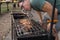 Caucasian close-up hands cooking beef steak on the grill net on coal bbq outdoors. Back yard bbq party in summer or