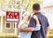 Caucasian Couple Facing Front of Sold Real Estate Sign and House