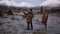 A caucasian couple launches drone at the field in front the mountains with snowy peaks on the background. Man operating