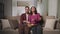 Caucasian couple watching TV at night sitting on sofa with bowl of popcorn.