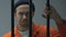 Caucasian criminal looking at camera through prison bars, waiting for judgment