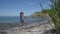 Caucasian curly woman with sarong and hat walking on a beach