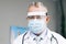 Caucasian Doctor in Glasses is Wearing a Transparent Protective Face Shield, Mask and Overalls in a Hospital Room. Covid