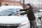 Caucasian driver cleans windshield and removes snow from rubber wipers of his car