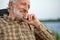 Caucasian elderly man with gray hair sit on chair in nature while camping, smiling