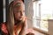 Caucasian elementary schoolgirl leaning on glass window in classroom