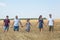 Caucasian family holding hands together while standing on yellow wheat field, Caucasian people full length portrait