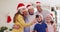 Caucasian family wearing santa hats and face masks around their necks taking a selfie together using