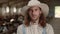 Caucasian farmer in hat standing at stable with goats