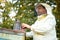 Caucasian farmer tending his bee hives with bee smoker on his private farm with homemade bee boxes