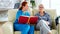 Caucasian female assistant in nursing home reading a book to an elderly retired woman