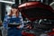 Caucasian female auto mechanic uses a special computer to diagnose faults.
