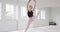 Caucasian female ballet dancer practicing ballet during a dance class in a bright studio