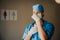 Caucasian female doctor or surgeon in scrubs preparing for surgery, medical gloves and mask